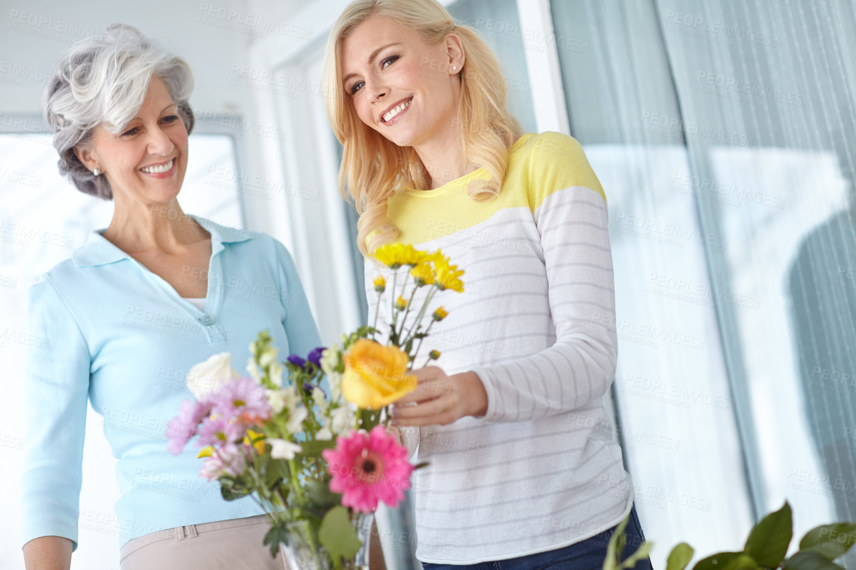 Buy stock photo Smile, mom and happy woman with flowers in home together with joy, love and wellness for affection. Mothers day, senior and daughter bonding in lounge with family, parent and gift present in Germany