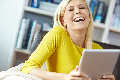 Buy stock photo Beautiful young content woman sitting on the sofa holding and using a digital tablet at home alone. One cheerful female relaxing and browsing online using social media on technology on a couch