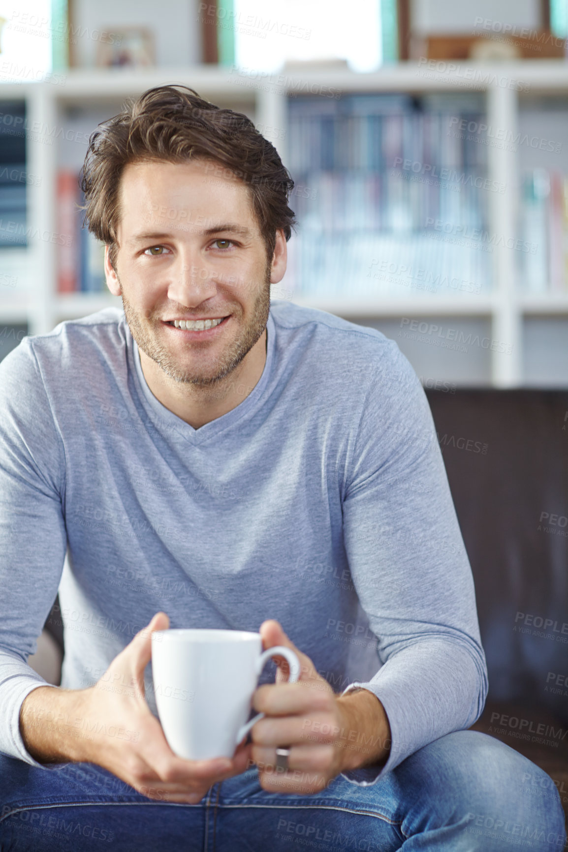 Buy stock photo Shot of a handsome man sitting on the sofa and enjoying a hot drink