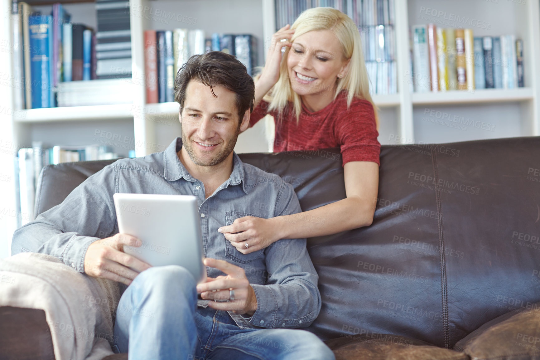 Buy stock photo Cropped shot of a young man using a digital tablet while his girlfriend watches from behind