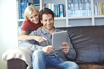 Buy stock photo Shot of an attractive young woman pointing at the screen of the digital tablet that her boyfriend is using