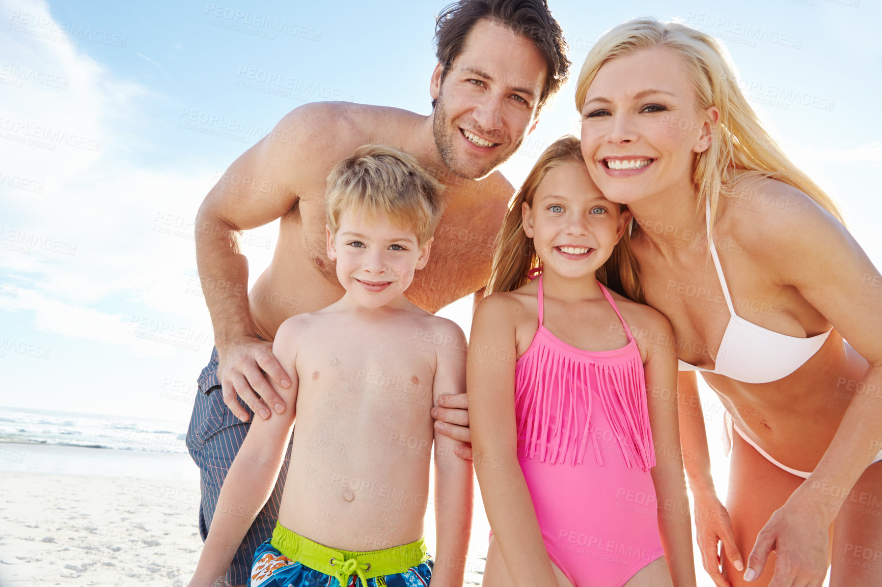 Buy stock photo Portrait of a happy young family enjoying a sunny day at the beach 