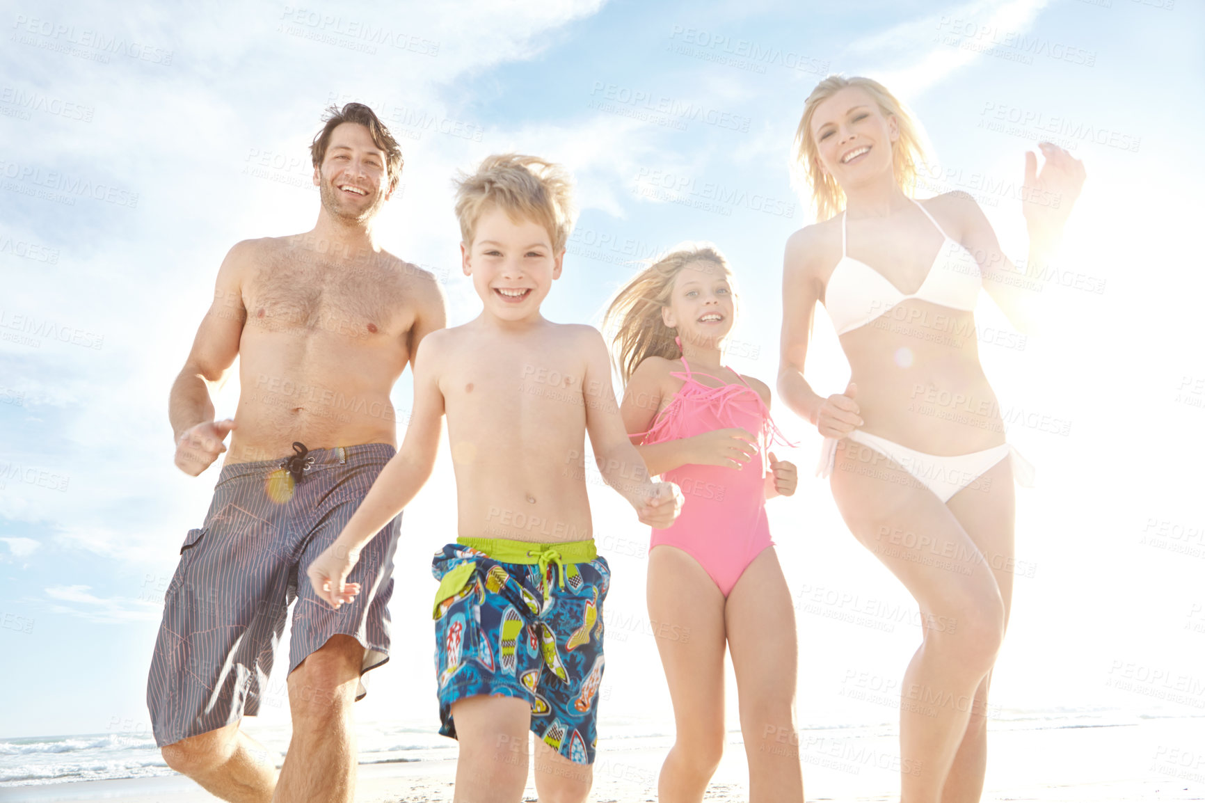 Buy stock photo Portrait of a happy young family enjoying a sunny day at the beach 