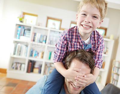 Buy stock photo Shot of a young boy covering his father's eyes while sitting on his shoulders
