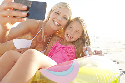 Buy stock photo Cropped shot of a young mother and daughter taking a picture of themselves on a beach