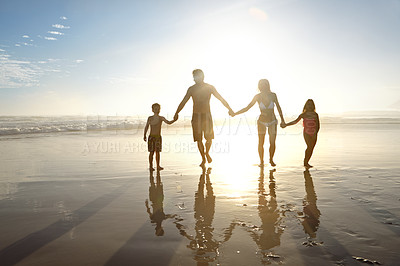 Buy stock photo Holding hands, summer and sunset with family on beach, walking together for bonding on holiday. Flare, happy or people with mother, father and children on sand by ocean or sea for love or vacation