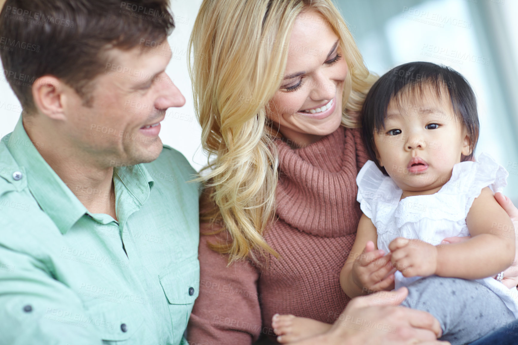 Buy stock photo Couple, adoption and asian child for family in home, love or girl for foster care. Together, bonding or support with married man and female person, diversity and baby for trust and hug in living room