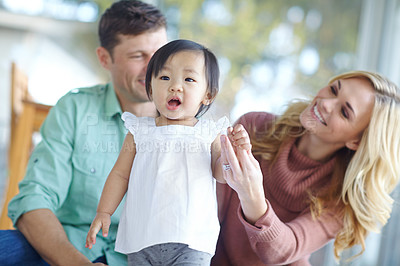 Buy stock photo Happy family, adopted baby and learning to walk in home for care, support or love. Mother, father or teaching cute foster kid first steps for balance, growth or help with parents in interracial house