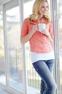 Buy stock photo Cropped shot of a beautiful young woman drinking coffee while looking out of her window at home