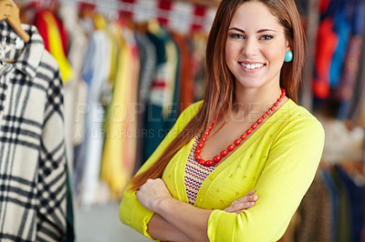 Buy stock photo A trendy young woman standing with her arms folded in a  bright fashion store