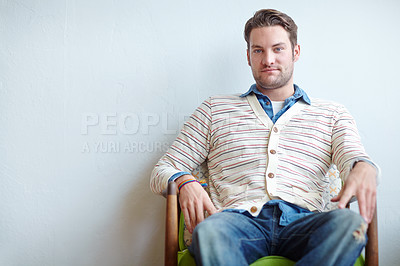 Buy stock photo Portrait of a stylish man sitting on a vintage armchair inside against a white wall with copyspace. Relaxed young male in retro style clothing looking confident. Fashion model showing thrifted clothes