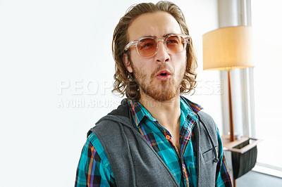 Buy stock photo A young man in a trendy outfit making a face while standing in a home interior