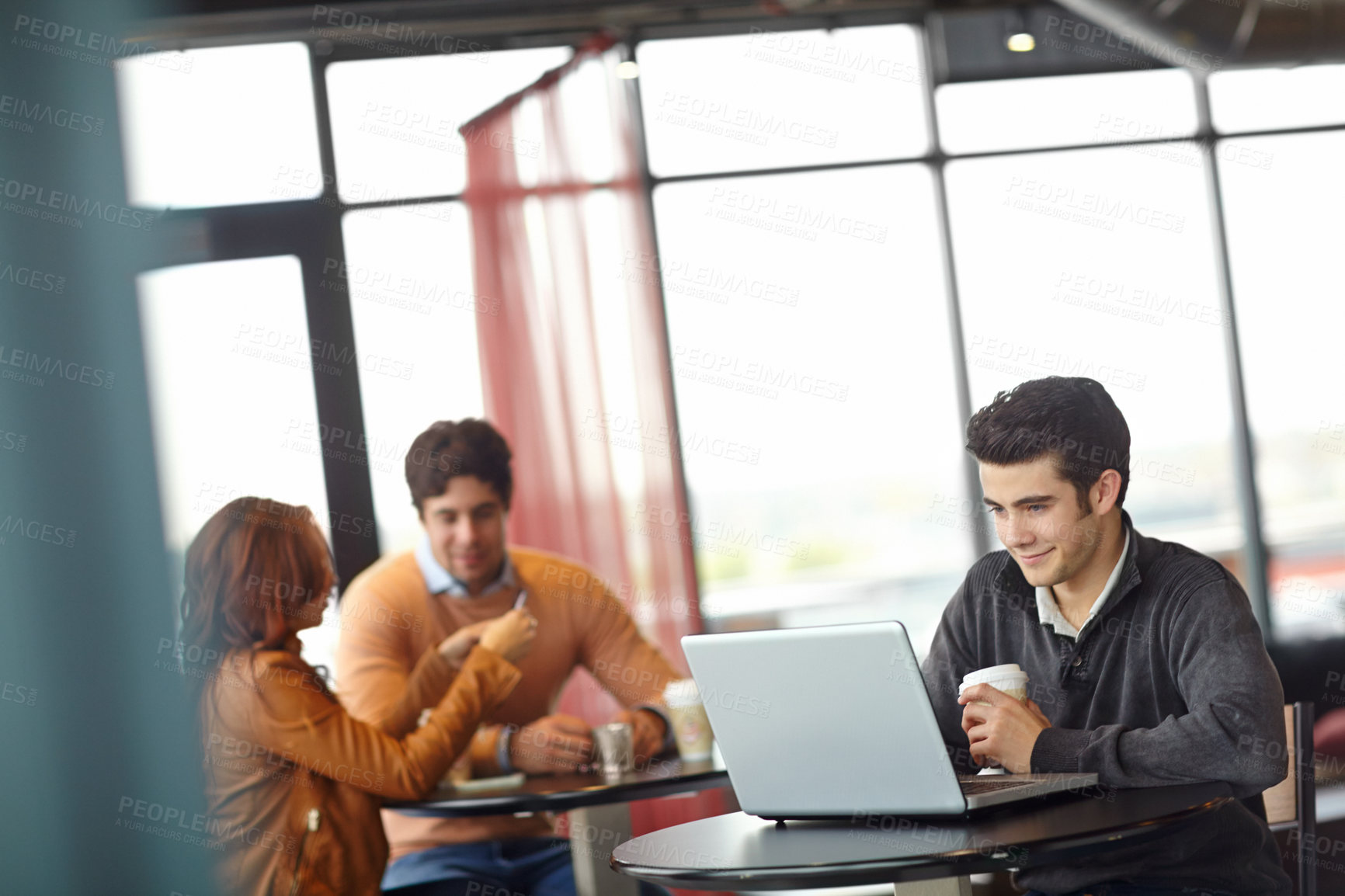 Buy stock photo A handsome young man using his laptop in a coffee shop