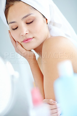 Buy stock photo Asian woman, bathroom and cosmetics with eyes closed, face or moisturizer bottle for change by mirror in home. Person, towel and grooming routine for skin, reflection or product for beauty in morning