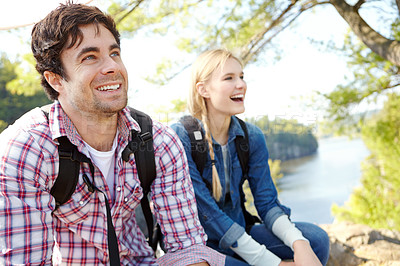 Buy stock photo Break, relax or happy couple hiking by river for travel, outdoor adventure or journey in nature with smile. Hikers, resting or people in forest on holiday vacation, fun trip or lake to explore park