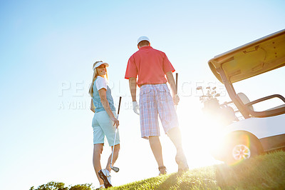 Buy stock photo Rear view shot of an attractive couple walking to their golf cart