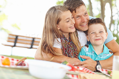 Buy stock photo Father hugging his daughter and son at the picnic table
