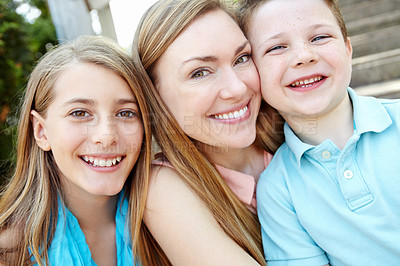 Buy stock photo Smiling attractive mother embracing her teen daughter and young son while outdoors