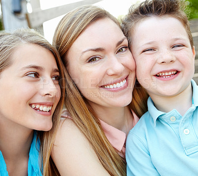 Buy stock photo Smiling attractive mother embracing her teen daughter and young son while outdoors
