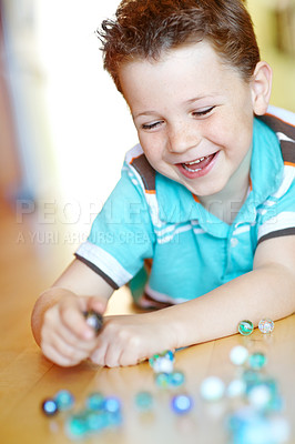 Buy stock photo Happy, child and boy play with marble on floor for funny game, relax and excited in home. Smile, kid and glass balls or toys on ground for creative collection, laugh or childhood development in house