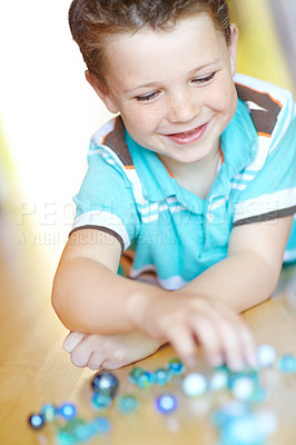 Buy stock photo Happy, kid and boy play with marble on floor for funny game, relax and excited in home. Smile, child and glass balls or toys on ground for creative collection, laugh or childhood development in house