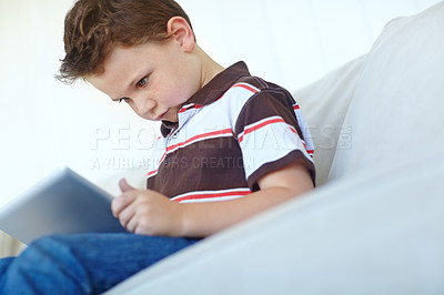 Buy stock photo Kid, tablet and relax on sofa in home, reading ebook and watch cartoon in living room in low angle. Boy, child and digital technology for internet addiction, scroll app and playing game for education