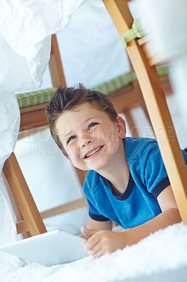 Buy stock photo Smile, tablet and kid thinking in home for ebook choice, decision or dream on floor. Happy, boy and child with technology in fort for internet, scroll app or learning game to relax on carpet in tent