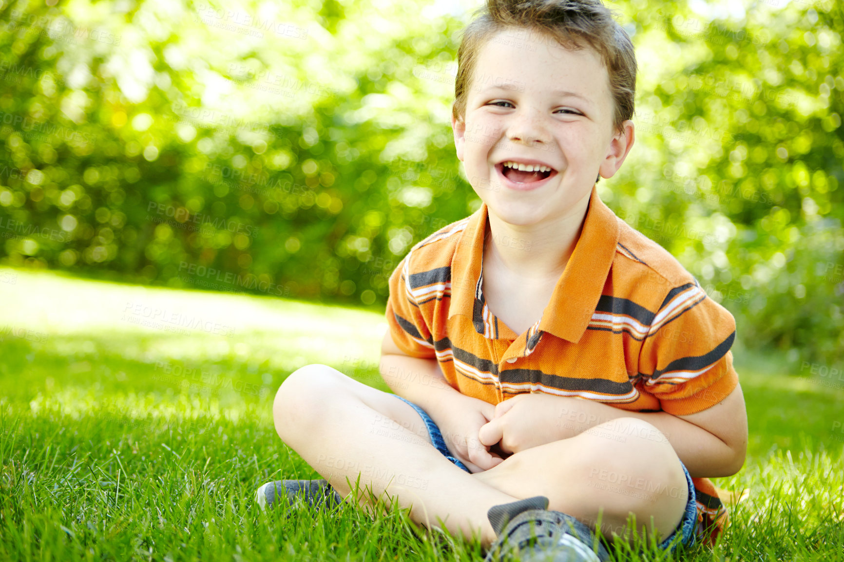 Buy stock photo Boy, outdoor portrait and child laughing on grass, forest adventure and countryside for development. Male person, happy kid and travel to France for joke, relax and healthy growth in environment