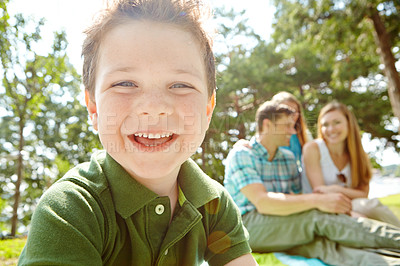 Buy stock photo A happy little boy sitting outdoors with his family on a sunny day