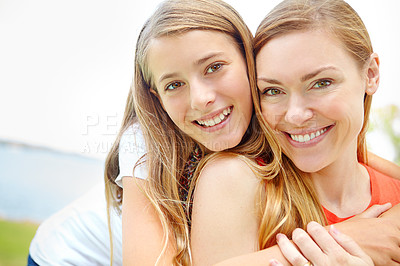 Buy stock photo A happy young daughter embracing her mother while outdoors