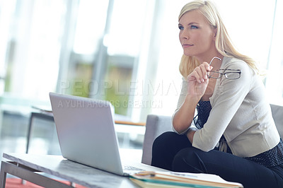 Buy stock photo Shot of a beautiful business woman staring ahead of her as she sits behind her laptop and paperwork