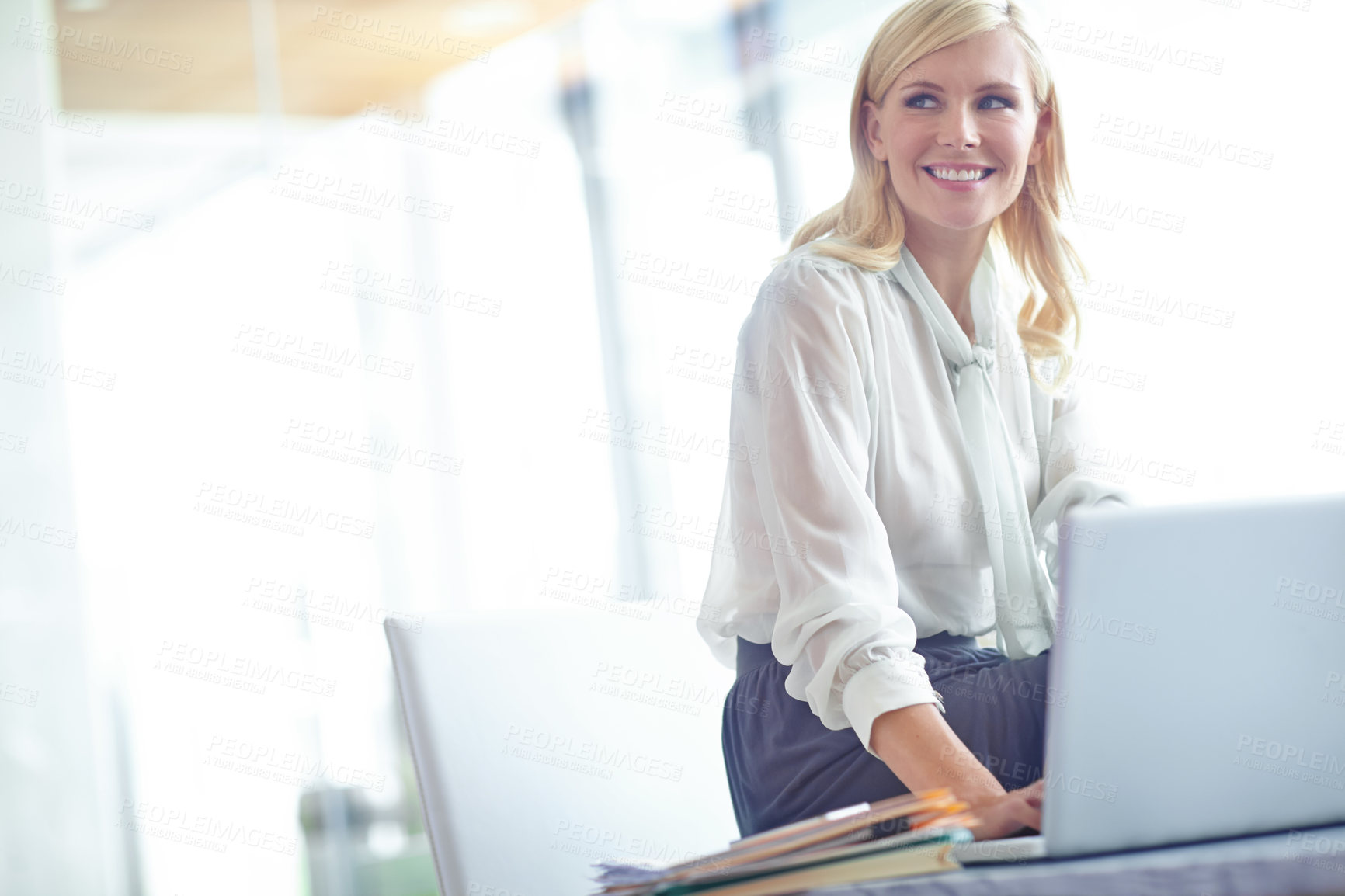 Buy stock photo Shot of a smiling business woman sitting at her desk with a laptop in front of her with copyspace