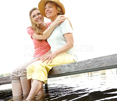 Buy stock photo Thinking, mature mother and daughter outdoor for reflection of family memories, relax and bonding. Smile, women and mom with hug for nostalgia of childhood thoughts, relationship and embrace on lake