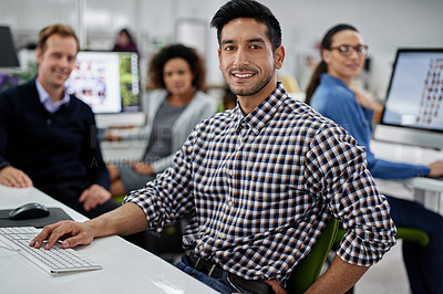 Buy stock photo Smiling businessman looking at the camera with his coworkers in the background