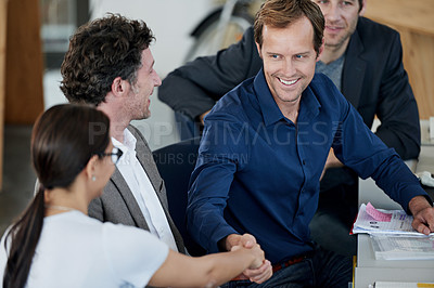 Buy stock photo Shot of two coworkers shaking hands in an office