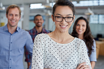 Buy stock photo Smart young woman smiling at the camera with colleagues in the background