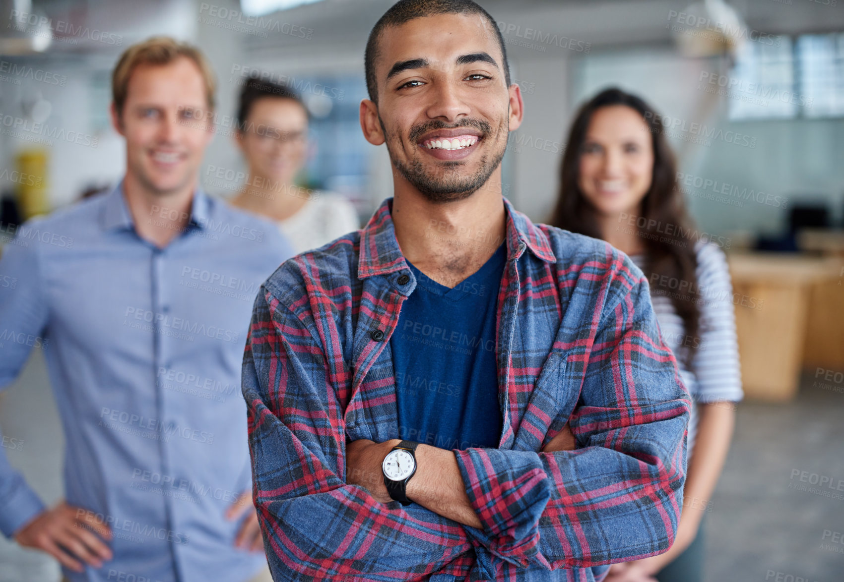 Buy stock photo Confidently smiling young man with his coworkers smiling behind him