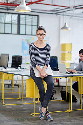 Buy stock photo Full length shot of a beautiful young woman leaning on her desk in a modern office