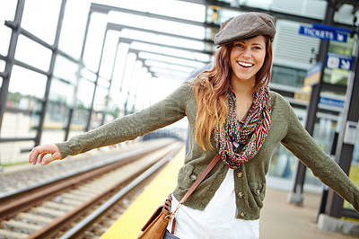 Buy stock photo Portrait of a smiling woman balancing along the railway of a train station with copyspace