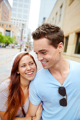 Buy stock photo A happy couple holding hands and walking along a city street with copyspace