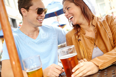 Buy stock photo A happy couple having beer at an outside bar