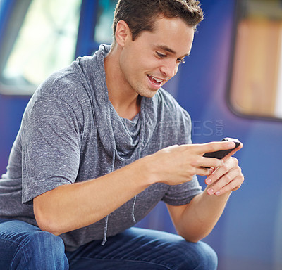 Buy stock photo A handsome young man typing on his cell phone