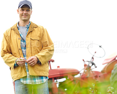 Buy stock photo Portrait of a farmer standing in a field with his tractor parked behind him - Copyspace