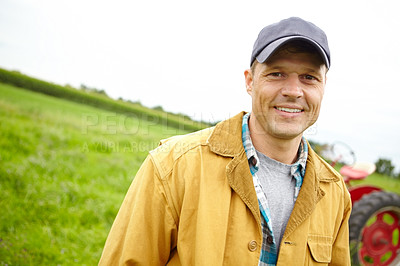 Buy stock photo Portrait of a smiling farmer in a field with a tractor parked behind him - Copyspace
