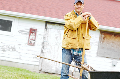 Buy stock photo Outdoor, farm and man in portrait with wheelbarrow, gardening and agriculture with confidence by shed. Countryside, male person and farmer with equipment for transport, cleaning and spade as tools