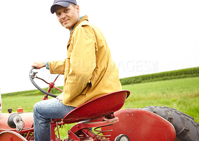 Buy stock photo Rearview of a smiling farmer driving his tractor on an open field