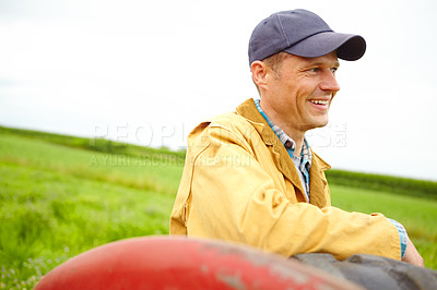 Buy stock photo A mid adult farmer leaning against a tractor on his farm
