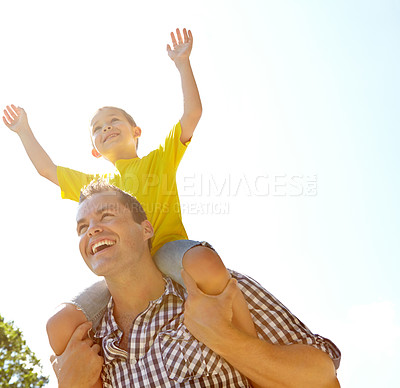 Buy stock photo Cute young boy sitting on his father's shoulders with his hands raised and smiling