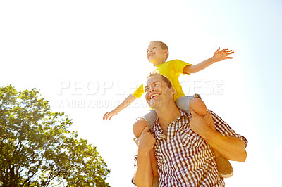Buy stock photo Father carrying his cute son on his shoulders while smiling widely