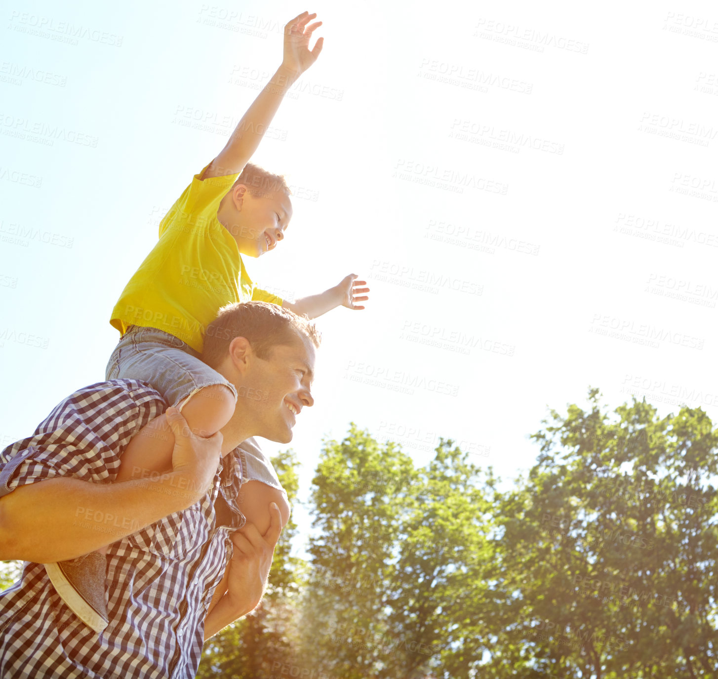 Buy stock photo Cropped shot of a cute young boy sitting on his father's shoulders and stretching his arms up